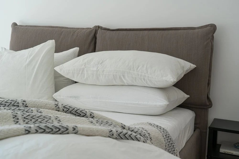 Cama com roupa branca e cabeceira estofada